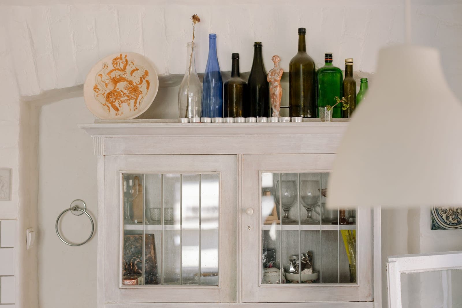 A glass-fronted drinks cabinet holding bottles and glassware