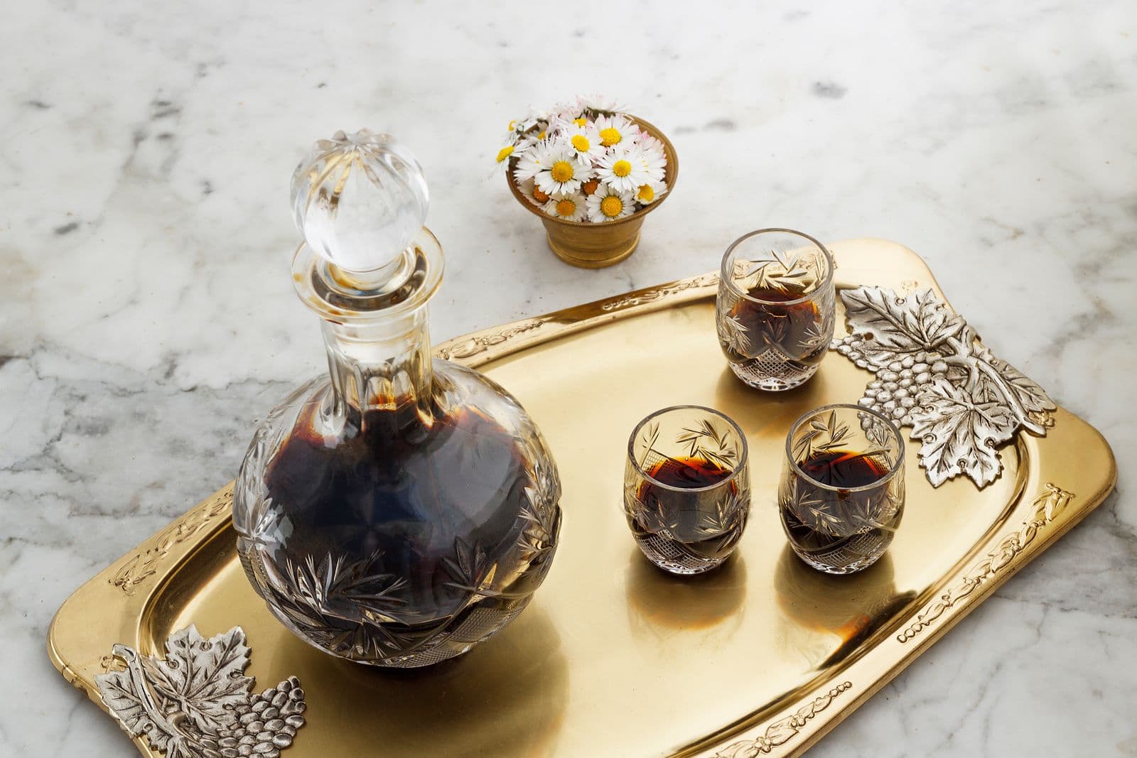 A decanter and small glasses on an ornate gold tray