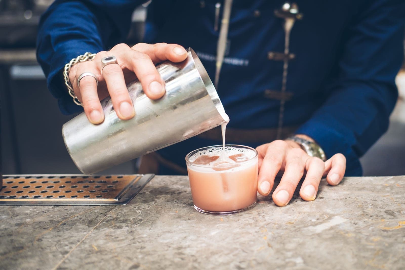 Hands shaking a cocktail shaker in a bright kitchen
