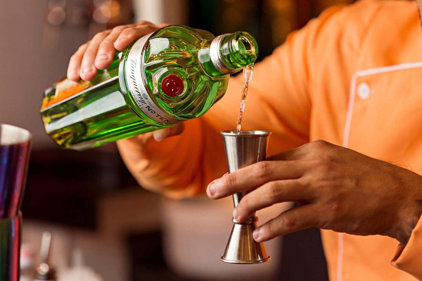 Measured spirit being poured into a jigger on a bright counter
