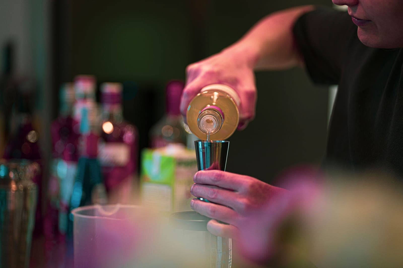 A jigger being used to measure a pour on a bright counter