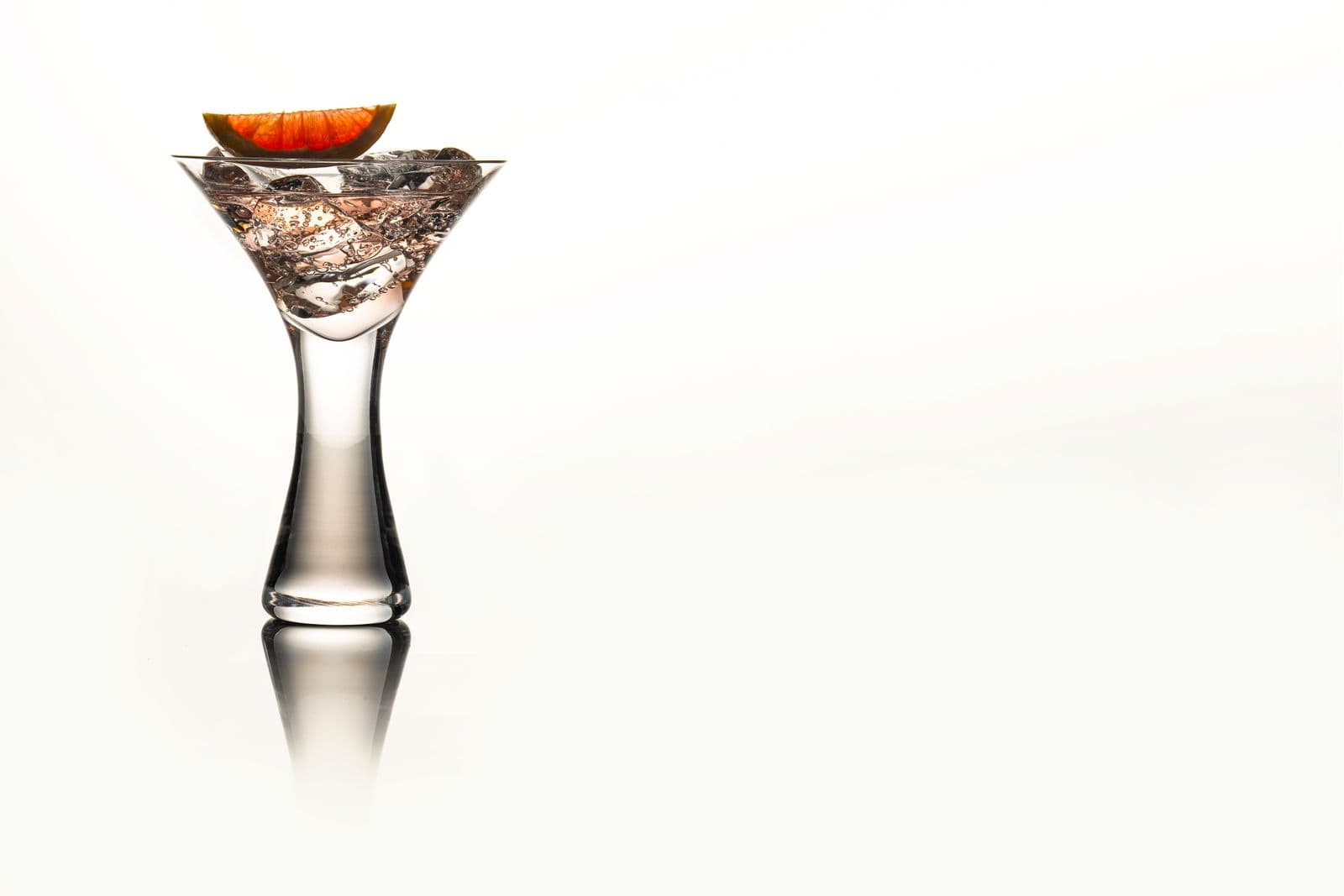 A martini glass filled with ice and garnished with an orange wedge