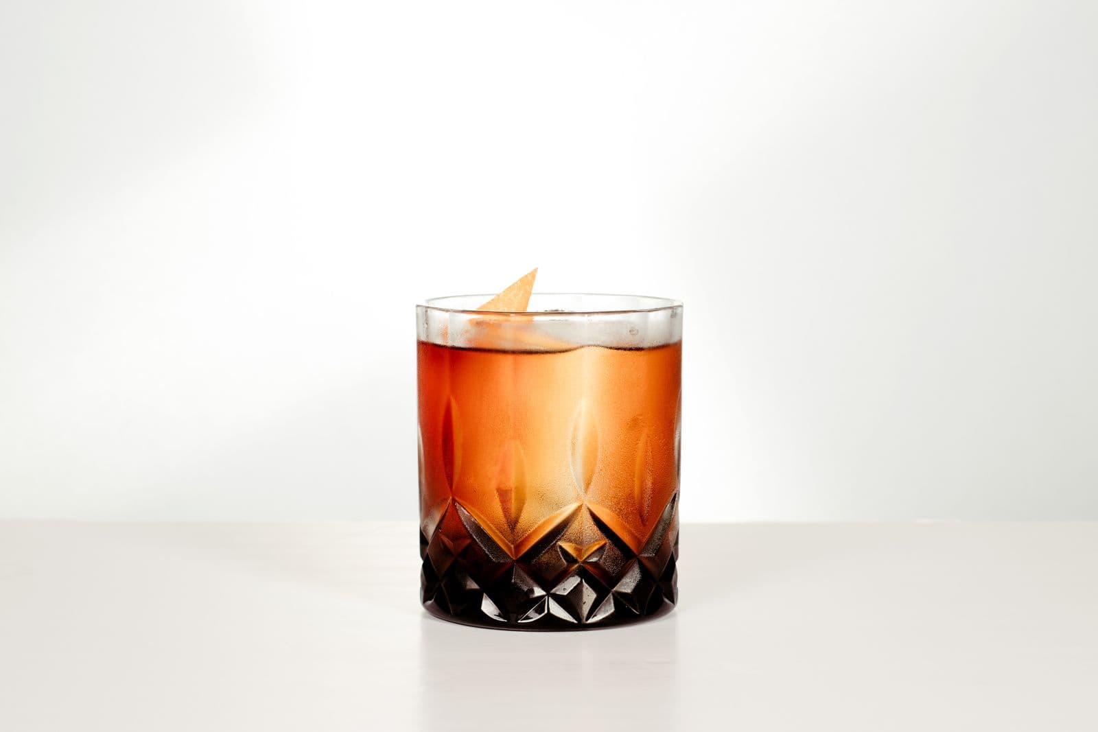 A whiskey cocktail with an orange twist served in a crystal glass