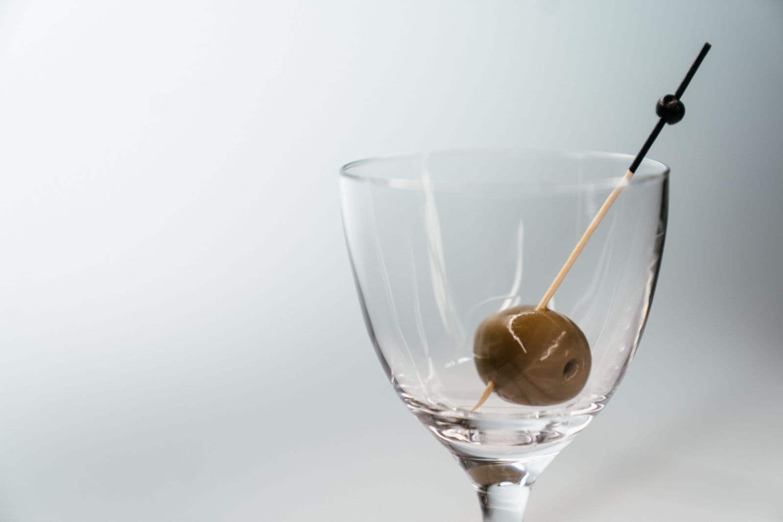 A martini glass with a single olive on a cocktail pick