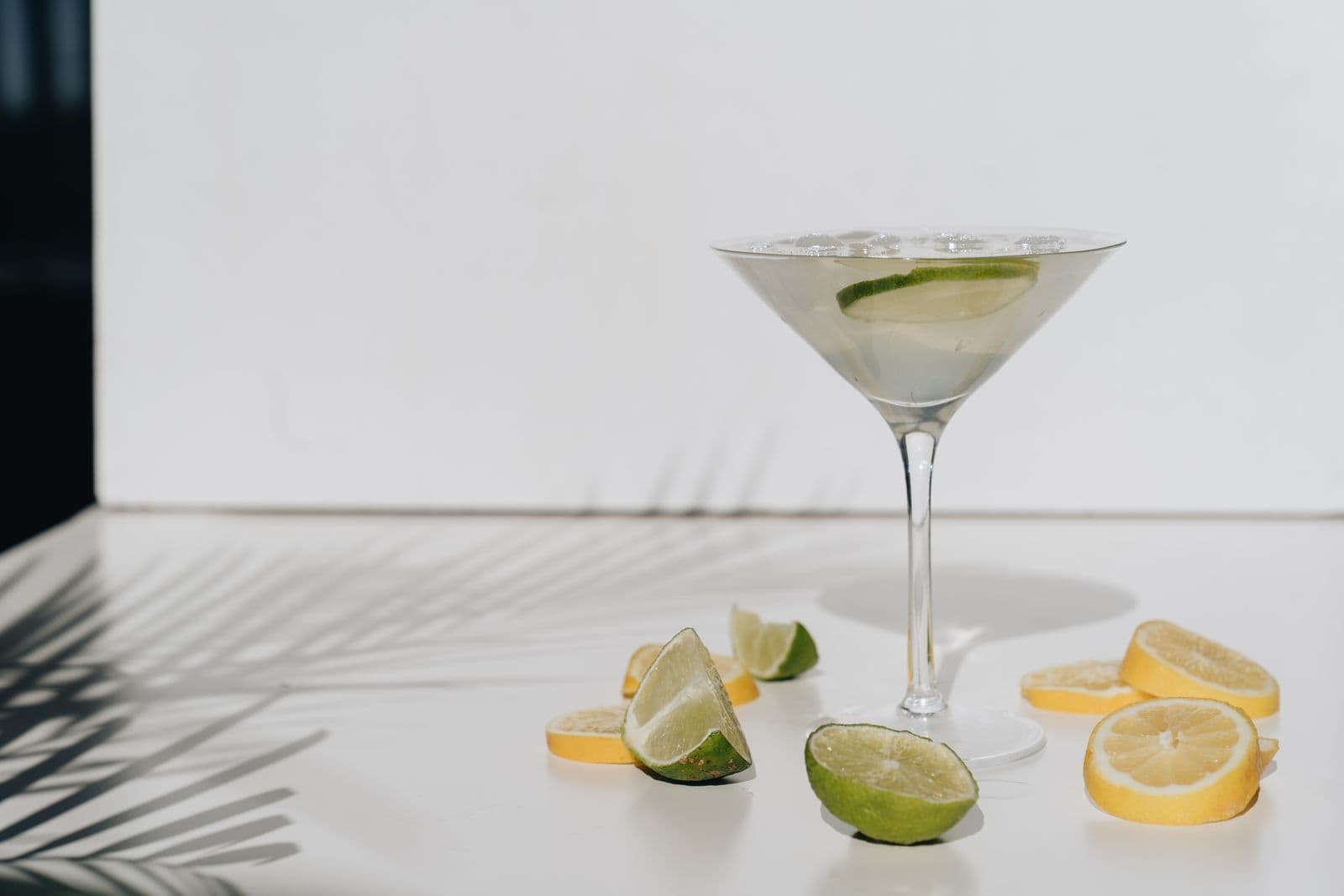A clear cocktail in a stemmed glass with lime and citrus slices