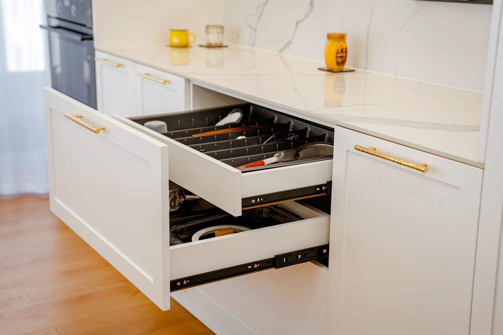 A cluttered kitchen drawer full of utensils in bright light