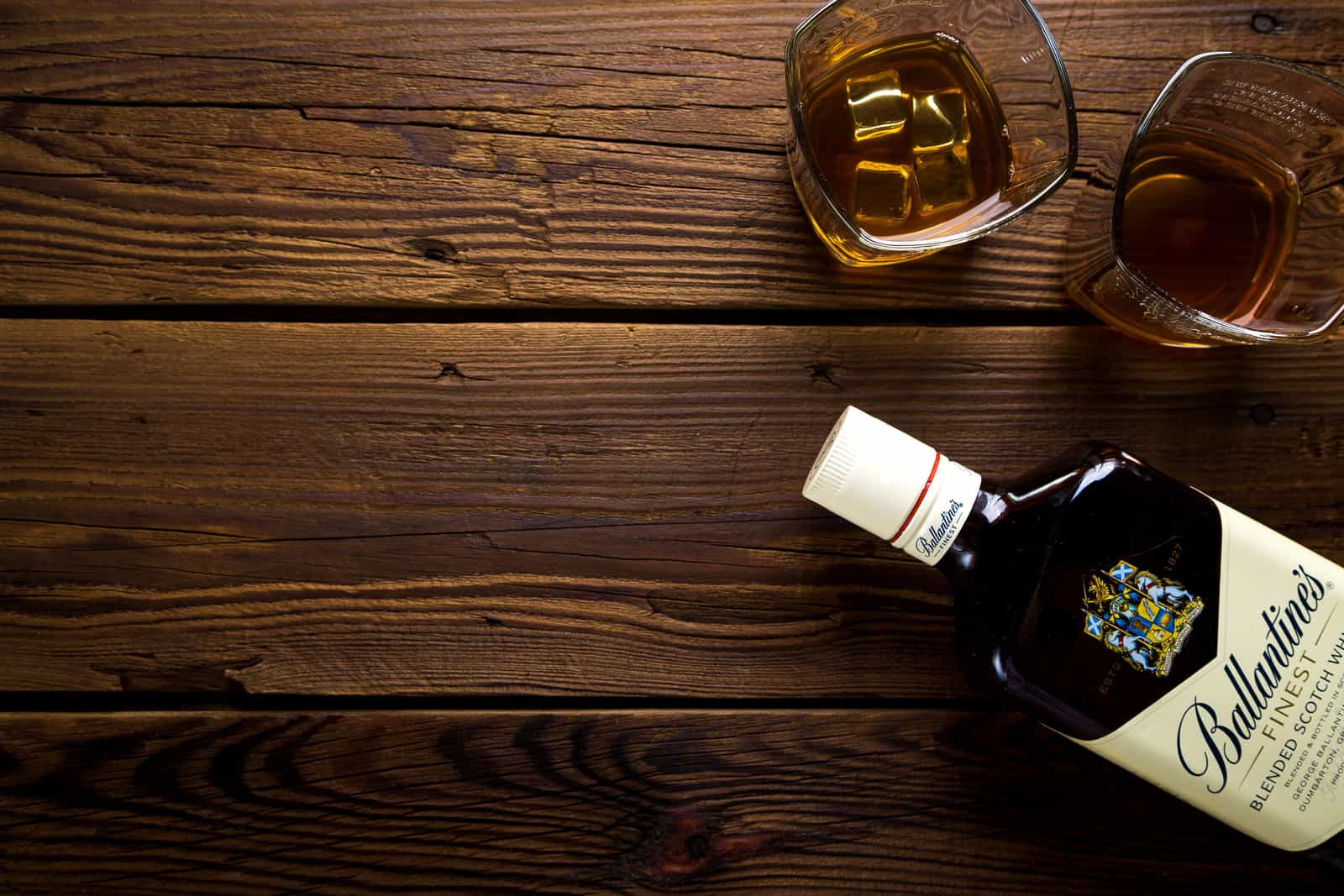 A whiskey glass on a bright wooden table in daylight