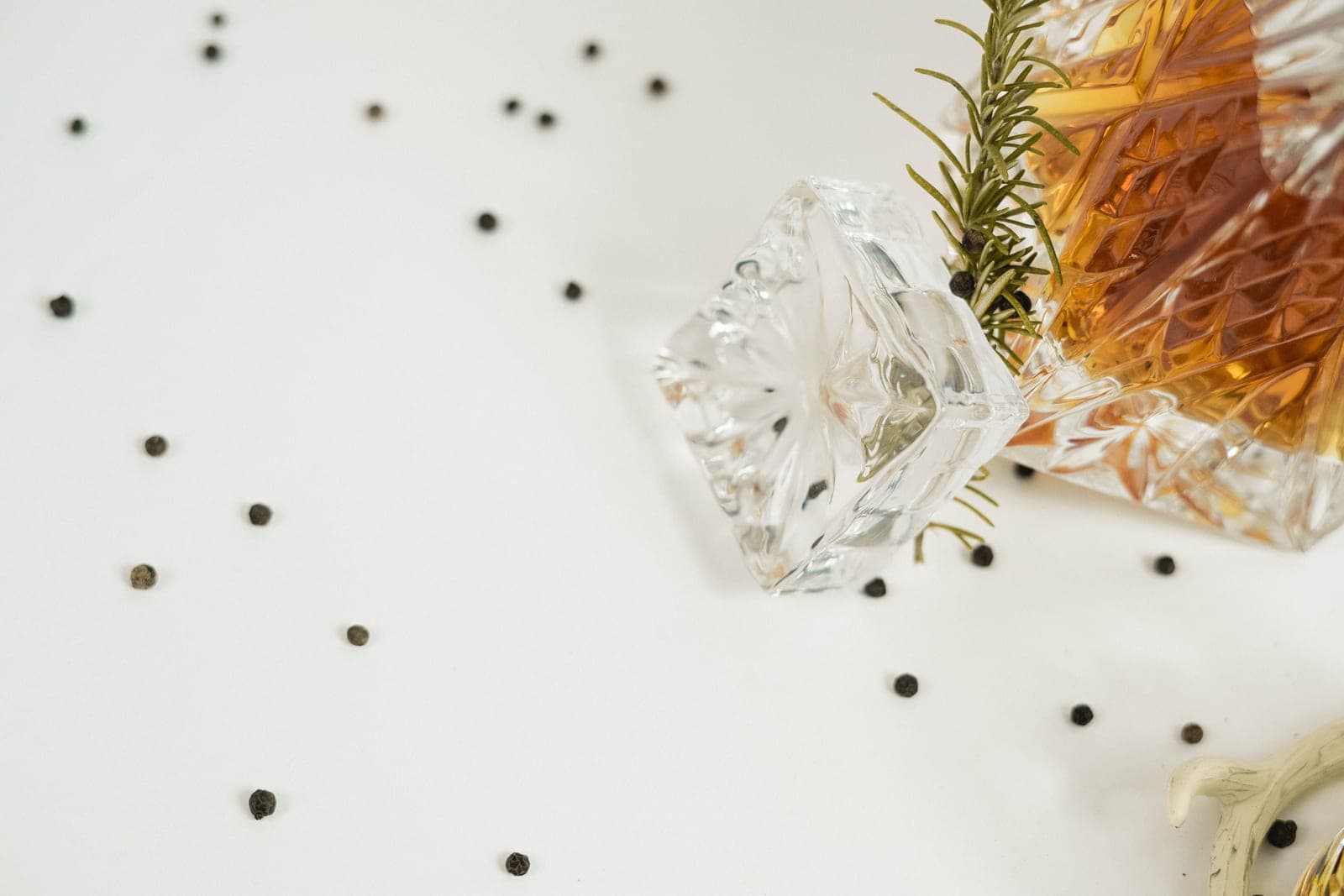 A cut-glass decanter with its stopper lying beside it on a white surface