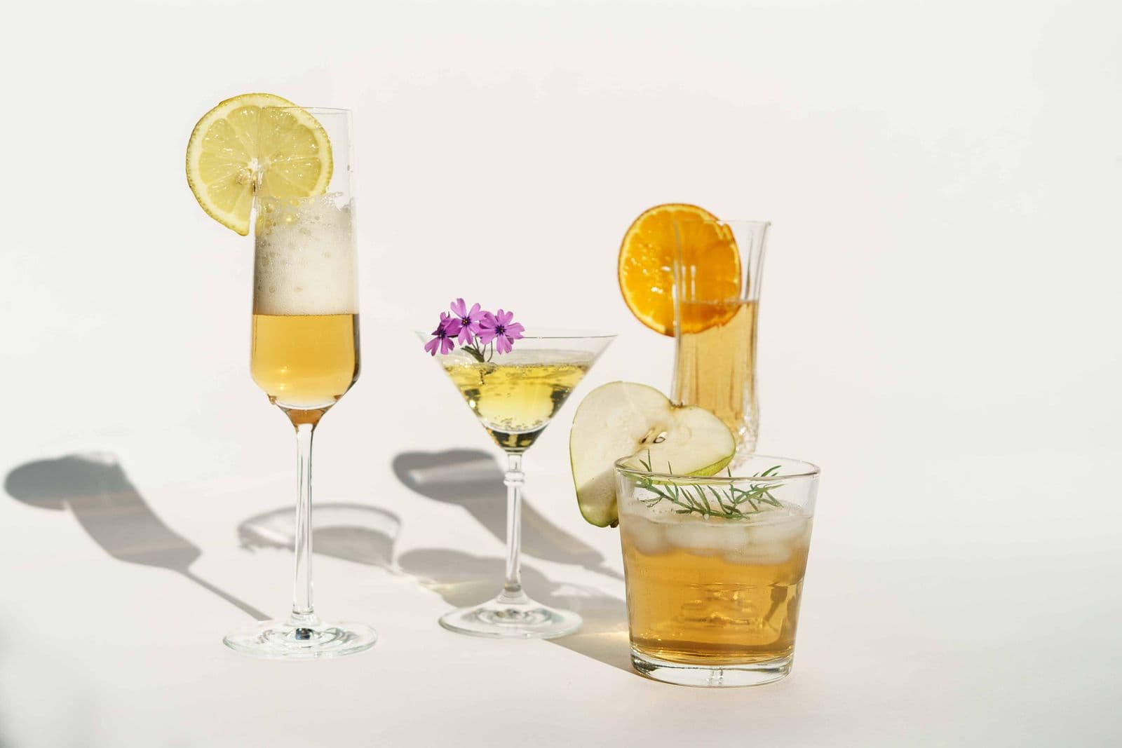 Cocktails in stemmed glasses garnished with fruit on a bright surface