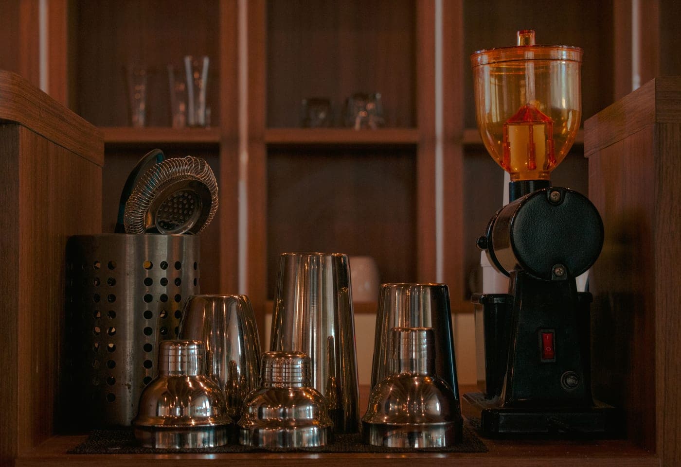 A cocktail shaker and bar tools arranged on a white kitchen counter in daylight