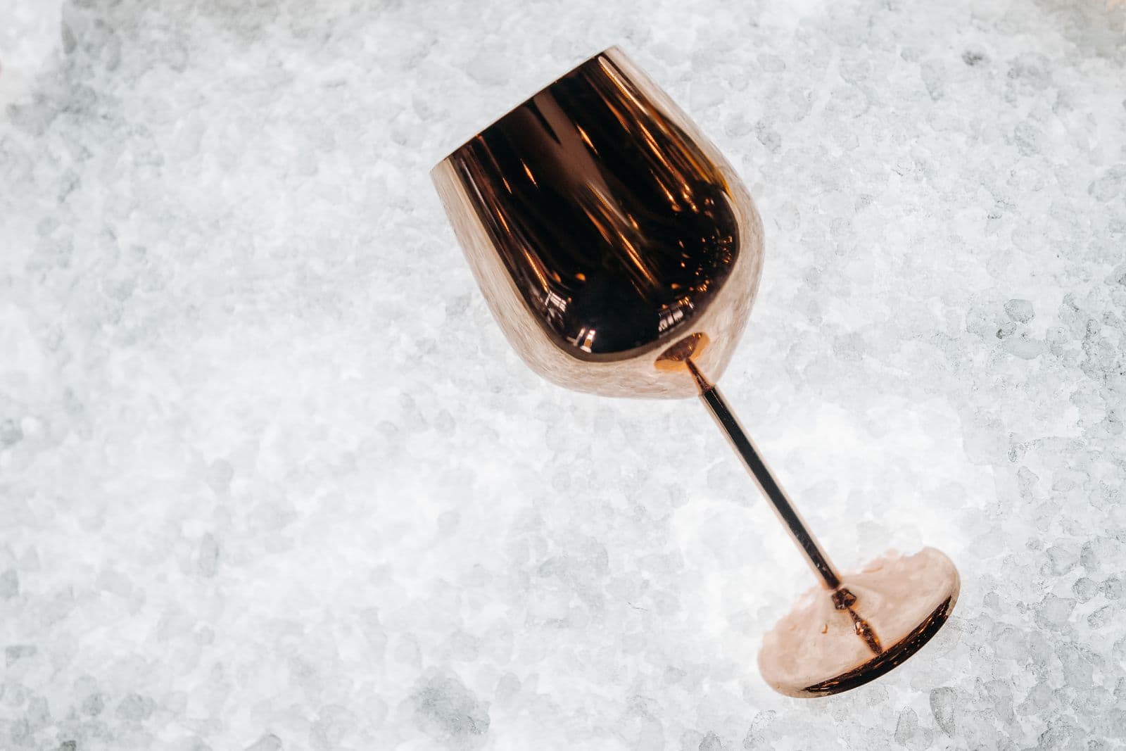 A copper cocktail glass resting on a bed of crushed ice