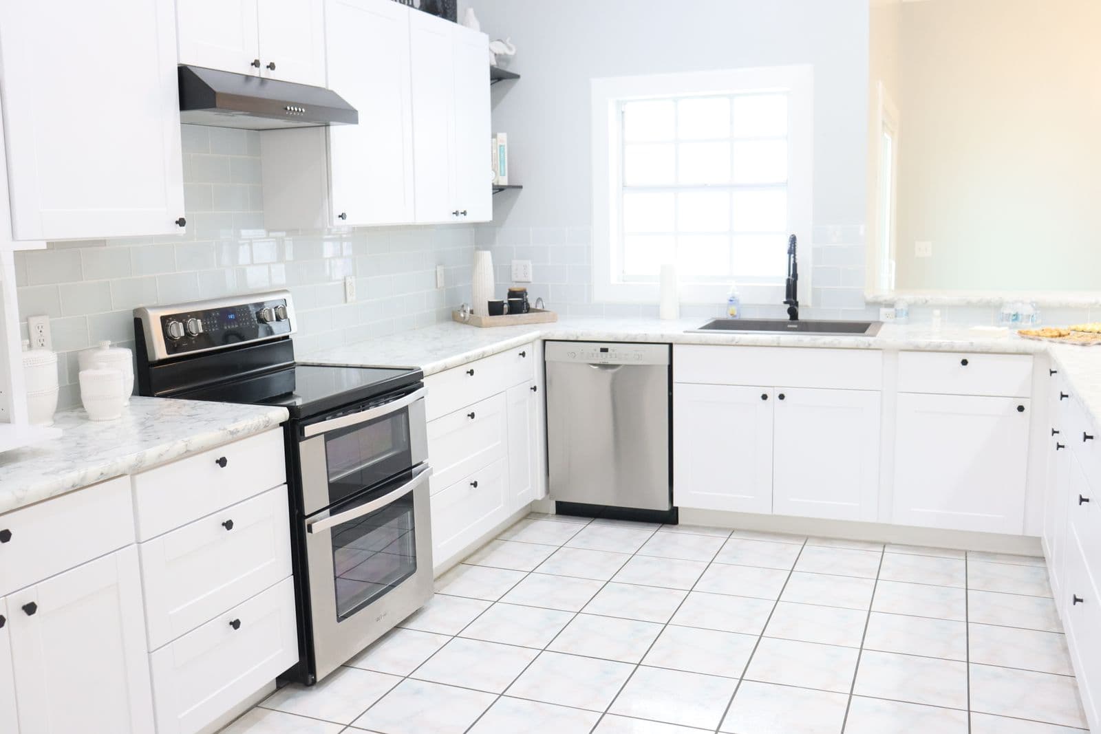 A bright modern kitchen counter with white cabinets and appliances