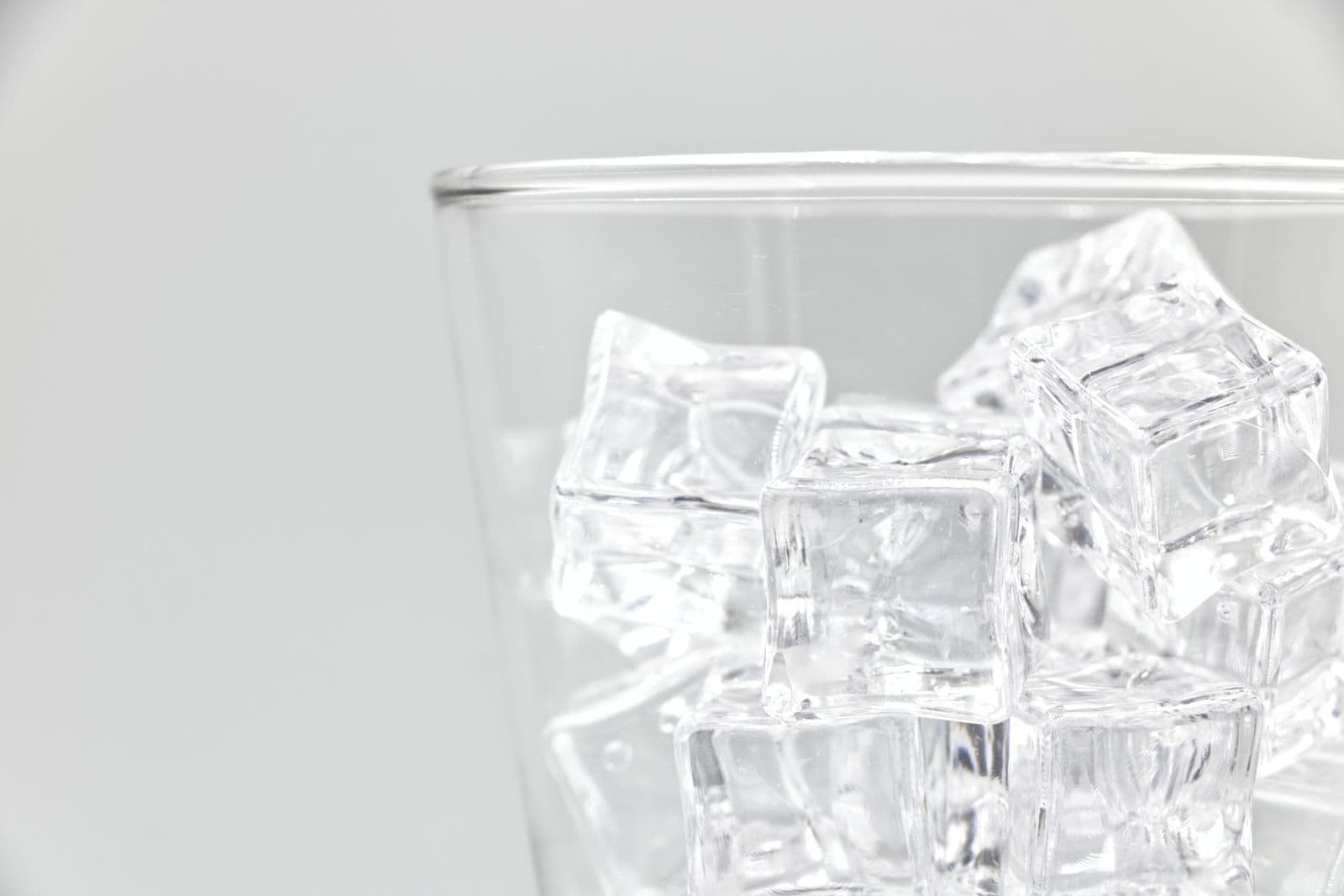 Ice cubes in a clear glass against a white background