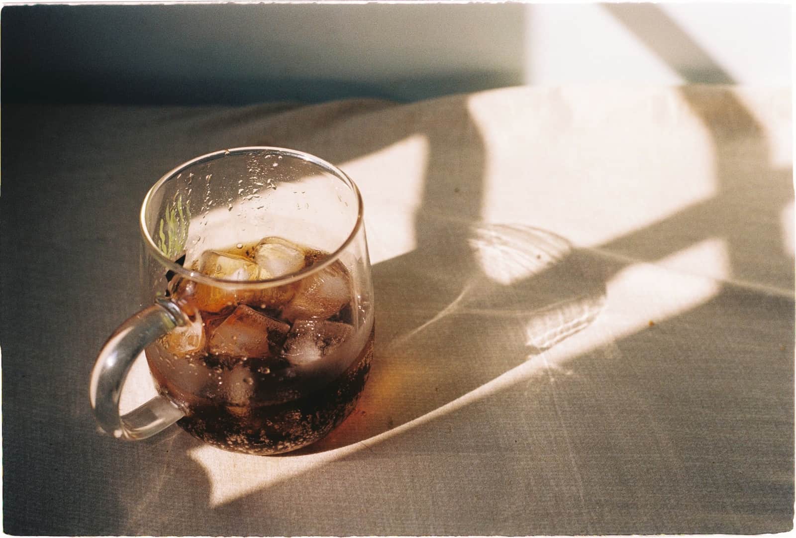 A large ice cube in a glass in bright daylight